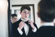 teen in tux looking in mirror, making final touches