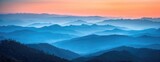 Fototapeta Na ścianę - Warm Sunset Glow Over Misty Mountain Layers: A Gradient of Blues to Oranges Across Softened Ridges