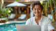 © Julija - happy young man with laptop sitting outside at Bali in hotel apartments near the swimming pool in tropical resort.