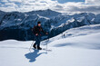 Man on mountain ski tour in the snow on sunny day, winter mountain panorama in background.