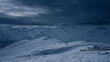 Two people on mountain ski tour during dramatic dark weather conditions, dark clouds in the sky.