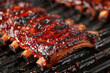 Juicy ribs sizzle on the barbecue grill. The succulent meat emits smoke and aroma over a natural charcoal fire, encapsulating the flavor of outdoor cuisine.