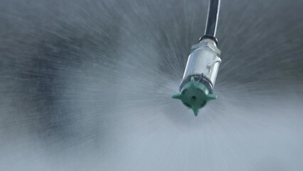 Wall Mural - Closeup of agricultural sprinkler head spraying water drops at field, slow motion