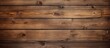A weathered wooden wall stands prominently against a solid brown background. The texture of the wood is visible, adding character to the simple yet striking composition.