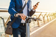© InsideCreativeHouse - Cropped image of businessman using phone on his electric scooter. Closeup photo of man in business formal attire unlocking e-scooter in mobile application