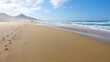 2 Wanderer am Strand von Cofete mit Dunst und Wellen und Sonnenschein