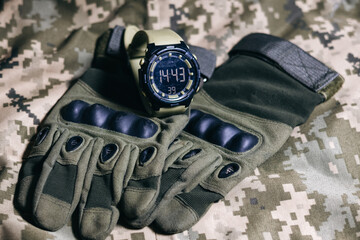 Wall Mural - Tactical military gloves and watch on the khaki camouflage uniform. Soldier ammunition.