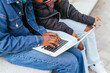 © ADDICTIVE STOCK - A close up view captures the anonymous hands of two young women, likely sisters, working together on a laptop, a symbol of collaborative technology use