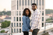 © sofiko14 - African American people in love waking at evening on rooftop of modern building. Young girlfriend and boyfriend having date after work. Urban portrait of loving couple.