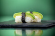 Close up of two pieces of avocado nigiri wrapped around with a strip of Nori with green background