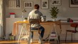 © Robert Anto - A young man in a casual hoodie works at a minimalist desk in a bright, stylish home office, reflecting a blend of comfort and productivity.