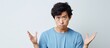 Young Chinese Man in Blue Shirt Showing Displeasure with Hand Gesture Against White Wall Background