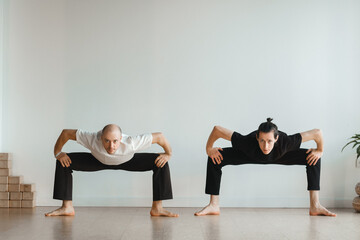 two young athletes practice yoga in the gym. Joint training, indoors, studio. The concept of a healthy lifestyle