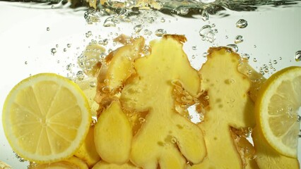 Fototapete - Super Slow Motion of Falling Ginger and Lemon Pieces into Water. Isolated on Colored Background. Filmed on High Speed Cinema Camera, 1000 fps. Speed Ramp Effect.