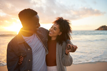 Wall Mural - Smiling multiethnic couple standing together on a sandy beach at dusk