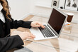 Young happy professional business woman employee sitting at desk working on laptop in modern corporate office interior.