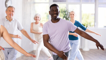 Wall Mural - Group of multiethnic mature active people dancing classical dance movements in studio