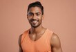© kotlyarn - A smiling man in an orange tank top exudes a friendly and approachable vibe against a peach background.