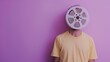 Creative depiction of a person with a vintage film reel for a head on a purple background