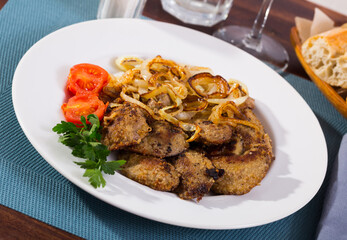 Wall Mural - Fried rabbit liver served on white plate with grilled onion and cherry tomatoes