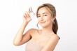 © Shutter B - Attractive young Asian woman holding a cosmetic spray bottle, smiling on white background. Clean fresh bare skin concept. Facial treatment, Perfect skin, Natural make up.