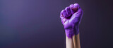 Fototapeta Zwierzęta - Raised purple painted fist of a woman in protest on March 8 on a purple background