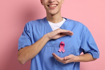 Poster - Mammologist with pink ribbon on color background, closeup. Breast cancer awareness