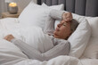 Menopause. Woman suffering from headache in bed