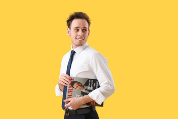 Wall Mural - Young businessman with magazine on yellow background