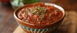 A bowl filled with deliciously traditional spaghetti sauce sits on a rustic wooden table. The sauce is a perfect blend of classic ingredients, bursting with flavors and aromas.