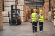 © chokniti - Engineer team standing walking in warehouse examining hardwood material for wood furniture production, Worker check stock, Technician man and woman working on quality control in lumber pallet factory