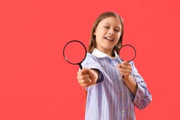 Little girl with magnifiers on red background