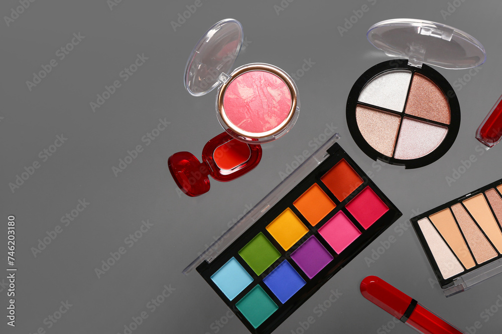 Beautiful palettes of eyeshadows and different decorative cosmetics on grey background