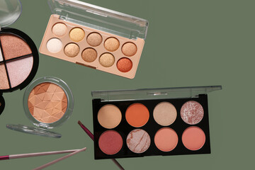 Beautiful palettes of eyeshadows and brushes on green background