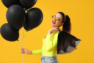 Sticker - Beautiful woman with shopping bags and balloons on yellow background. Black Friday sale