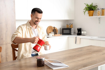 Wall Mural - Handsome man pouring espresso from geyser coffee maker into cup in modern kitchen