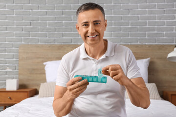 Sticker - Middle-aged man taking pill from pillbox in bedroom