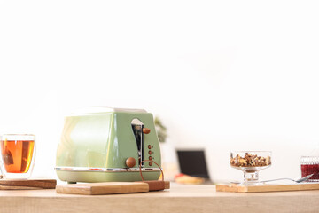 Canvas Print - Modern toaster with cup of tea, nuts and jam on wooden counter in kitchen