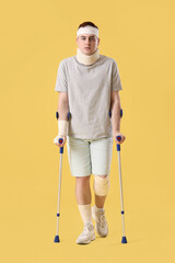 Sticker - Injured young man after accident with crutches on yellow background