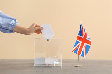 Wall Mural - Voting young woman with UK flag near ballot box on table at polling station