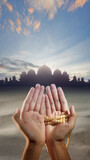 Fototapeta Morze - Muslim man's hand holding prayer beads is praying to Allah with a mosque and desert in the background.
