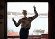 © Y.A./peopleimages.com - Peace sign, view and woman at window with lake, emoji and relaxed on holiday and vacation. Back, travel and female person on getaway, leisure and symbol on trip, retreat and acomodation for trip