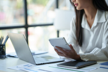 Accountant, Asian independent business woman uses calculator to calculate company financial results on table in office and business work history, tax, accounting, statistics and analytical concepts.