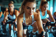 Young individuals - a group of women and men - engaging in indoor cycling in the gym for fitness, representing the concept of Health care