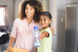 © Wavebreak Media - Biracial mother smiles at home in a home kitchen, showing a plastic bottle