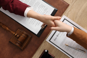 Canvas Print - Notary shaking hands with client at wooden table, top view