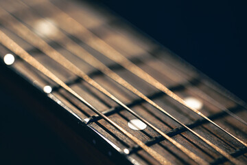 Part of an acoustic guitar, guitar fretboard on a black background.