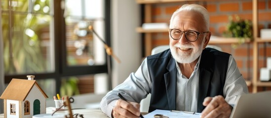 Poster - an older real estate agent sits confidently at a table with a laptop, writing in a planner. he expre