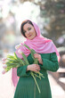 Beautiful woman with spring tulips flowers bouquet at city street. Happy portrait of girl smiling with pink tulip flowers