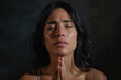 Hispanic woman prays to god on dark studio background. Cinematic effect